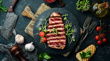 Siyah taş tabakta sebzeli sulu ton balığı bifteği pişirdim. Restoran yemeği. Deniz ürünleri. Kırsal tarzda. Düz Yat.