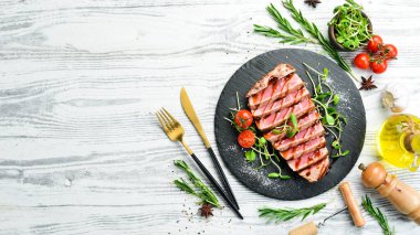 Siyah taş tabakta sebzeli sulu ton balığı bifteği pişirdim. Restoran yemeği. Deniz ürünleri. Kırsal tarzda. Düz Yat.