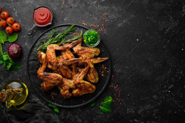 Siyah taş tabakta soslu ve baharatlı ızgara tavuk kanadı. Üst Manzara. Metin için boş alan.