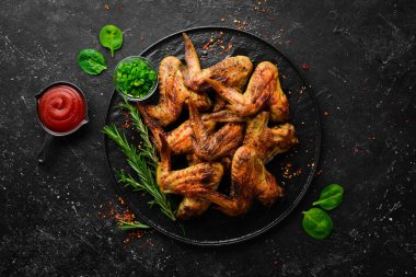 Siyah taş tabakta soslu ve baharatlı ızgara tavuk kanadı. Üst Manzara. Metin için boş alan.