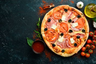 Pastırmalı, domatesli ve peynirli geleneksel pizza. Siyah taştan bir arka planda. Metin için boş alan.