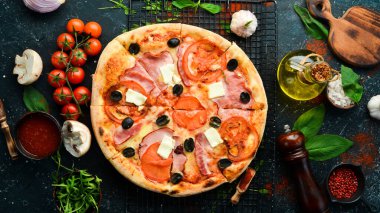 Pastırmalı, domatesli ve peynirli geleneksel pizza. Siyah taştan bir arka planda. Metin için boş alan.