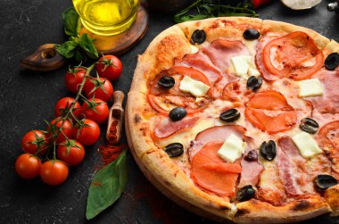 Pastırmalı, domatesli ve peynirli geleneksel pizza. Siyah taştan bir arka planda. Metin için boş alan.
