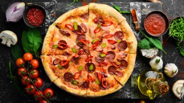 Sosisli ve biberli baharatlı pizza. Siyah taştan bir arka planda. Metin için boş alan.