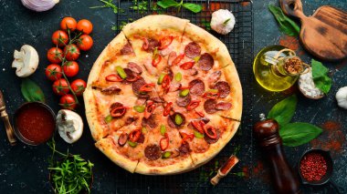Sosisli ve biberli baharatlı pizza. Siyah taştan bir arka planda. Metin için boş alan.