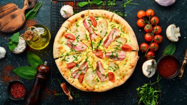 Tavuklu pizza, pastırma ve vişneli domates. İtalyan mutfağı. Siyah bir arkaplanda.