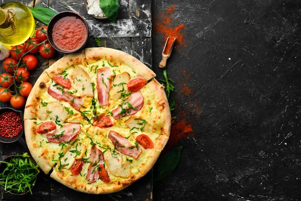 Tavuklu pizza, pastırma ve vişneli domates. İtalyan mutfağı. Siyah bir arkaplanda.