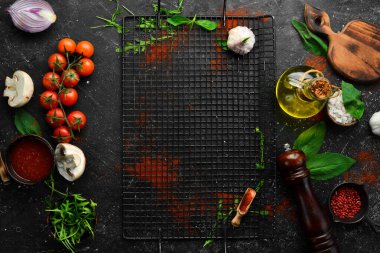 Mutfak mutfağı: kiraz domatesleri, soğanlar, baharatlar ve otlar. Siyah bir arkaplanda.