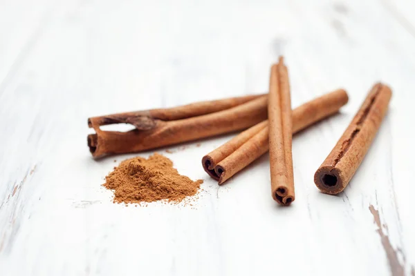 Canela molida y palitos de canela sobre fondo blanco — Foto de Stock