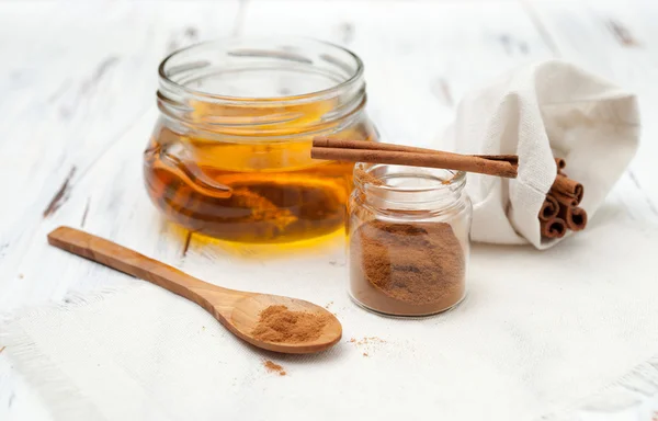 Canela molida, miel y palitos de canela sobre fondo blanco — Foto de Stock