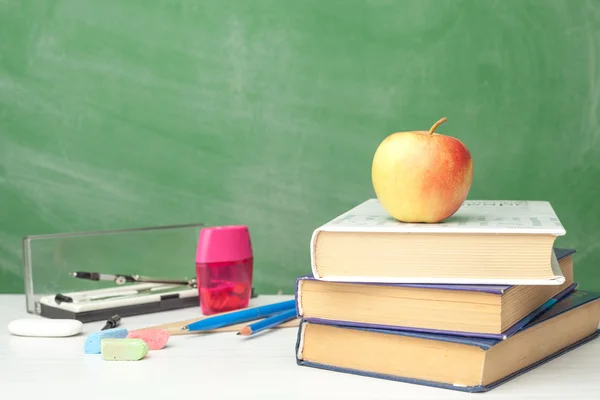 Boeken en benodigdheden voor de school op de tafel naast chalk Board — Stockfoto