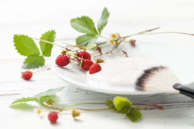 Beyaz ahşap masa üzerinde yaban çileği ile ekşi krema