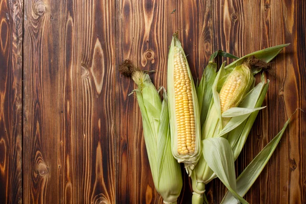 Raw cobs of young corn with leaves on a wooden table — Stock Photo, Image