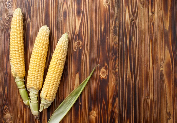 Raw cobs of young corn with leaves on a wooden table — Stock Photo, Image