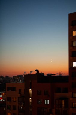 Günbatımından sonra gökyüzü arkaplanı yarım ay ile çok katlı bir yerleşim alanında