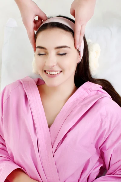 Mujer joven recibiendo masaje facial con los ojos cerrados en un spa s — Foto de Stock