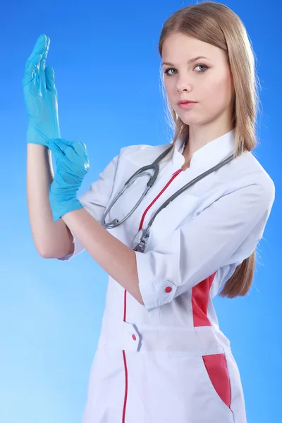 Retrato de una joven doctora con abrigo blanco y guantes azules — Foto de Stock
