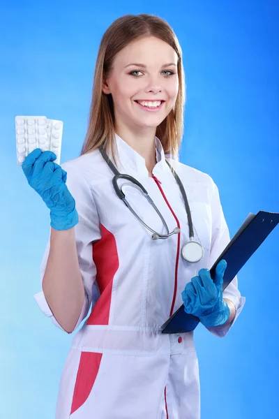 Χαμογελαστή γυναίκα γιατρό με έναν φάκελο στην ομοιόμορφη στέκεται στο εµποδίζουν — Φωτογραφία Αρχείου