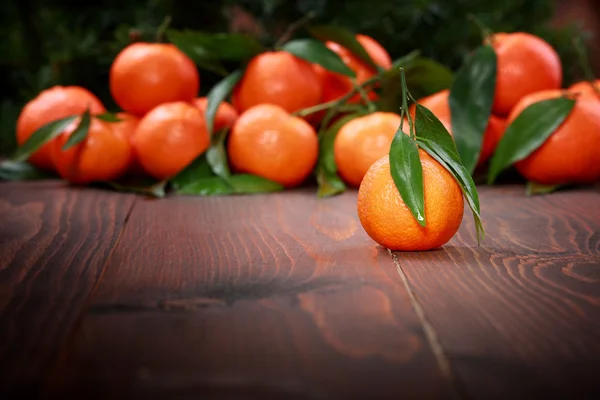 Mandarijnen met bladeren op houten oppervlak — Stockfoto