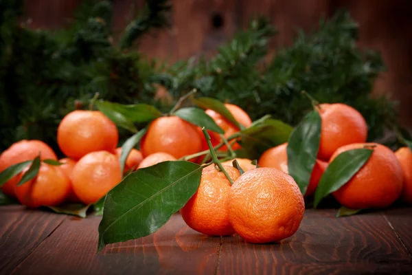 Mandarijnen met bladeren op houten oppervlak — Stockfoto