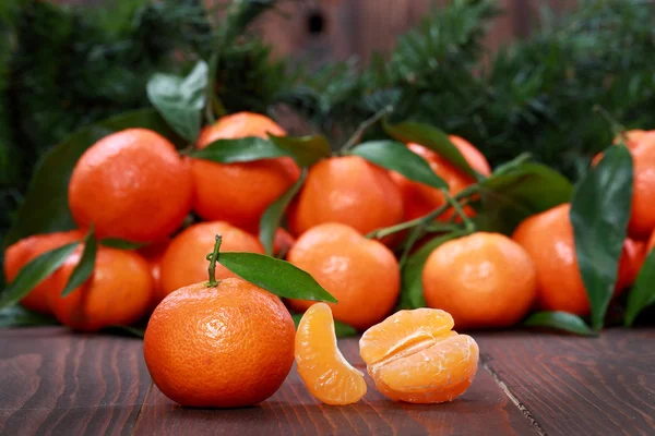 Mandarijnen met bladeren op houten oppervlak — Stockfoto