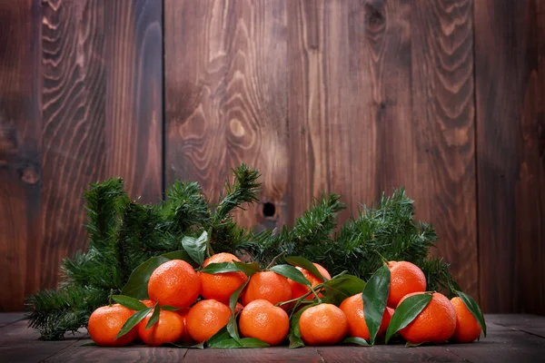 Mandarijnen met bladeren op houten oppervlak — Stockfoto