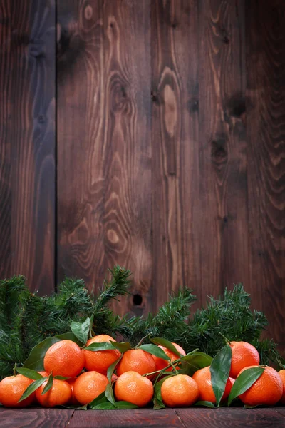 Mandarijnen met bladeren op houten oppervlak — Stockfoto