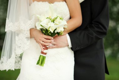 Gelin ve damat gelin buketi tutarak yakından