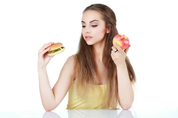 Jeune fille douteuse avec pomme et hamburger isolé — Photo