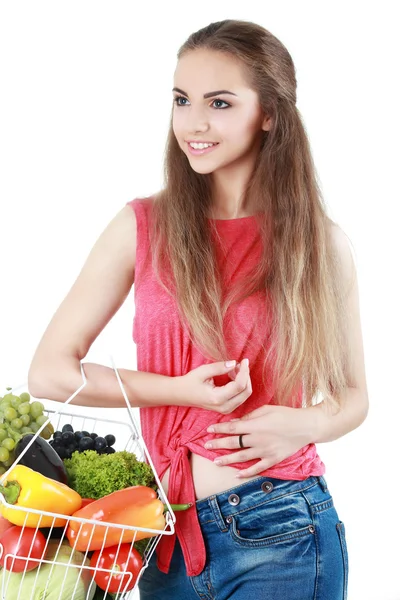 Mujer joven aislada sosteniendo cesta de verduras en respaldo ligero — Foto de Stock