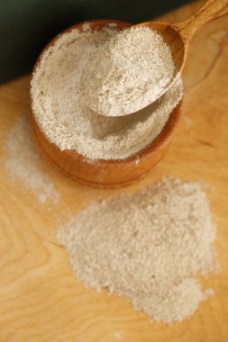 Ahşap zemin üzerinde kil bir kasede susam unu.