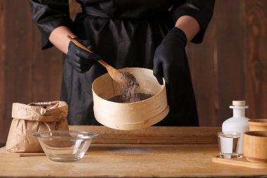 Mutfak masasında çiğ maya hamuru var. Erkek elleri mutfak havlusunu tutuyor.