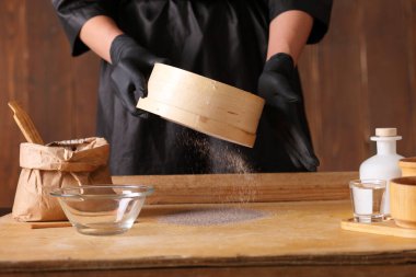 Mutfak masasında çiğ maya hamuru var. Erkek elleri mutfak havlusunu tutuyor.