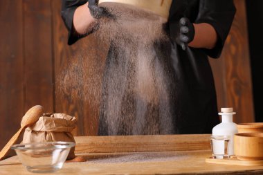 Mutfak masasında çiğ maya hamuru var. Erkek elleri mutfak havlusunu tutuyor.