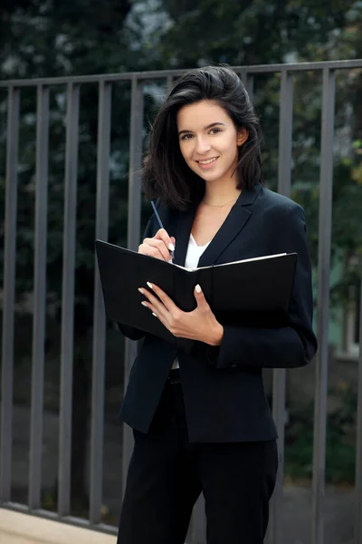 金属製の柵を背景にしたビジネススーツの若い女性 — ストック写真