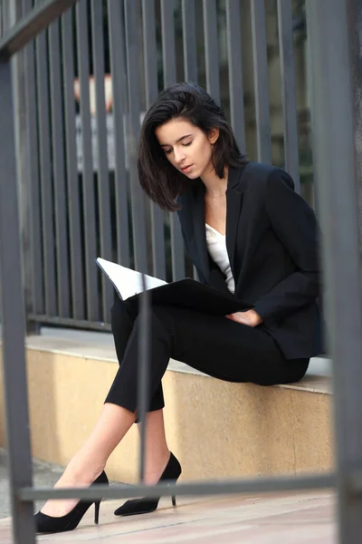 A young woman in a business suit on a background of a metal fence.