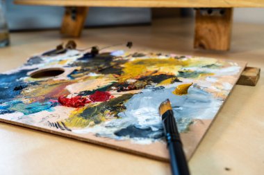 Evde rahatlamış bir sanatçının renkli yağlarıyla boya fırça ve palet.