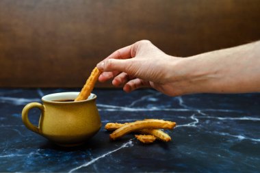 Mavi mermer arka planda churro ile bir fincan sıcak çikolata.