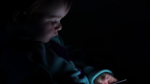 Лицо ребенка освещается светом смартфона — стоковое видео