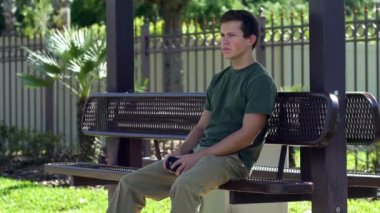 Adam telefonu kontrol bankta oturur