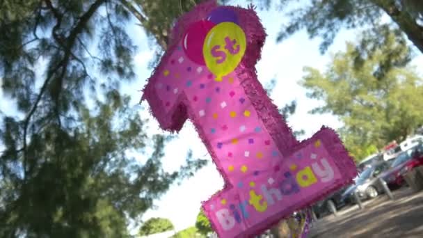 Pink 1st birthday piñata at the beach — Stockvideo