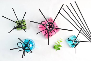 Lüks cam aromalı difüzyon şişesi beyaz oturma odasındaki beyaz masada mavi, yeşil ve pembe renkli yağ sergilenir.