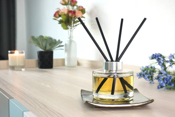 luxury aromatic scent reed diffuser glass bottle is used as room freshener on wooden table in the bedroom to create romantic and relax ambient with background of the flowers on the valentine day