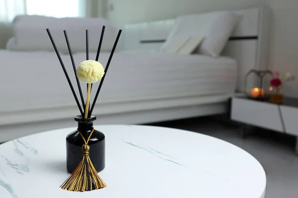 luxury aromatic scent of reed diffuser glass bottle is used as room freshener on the marble table in the bedroom to creat relax ambient with background of light from window and white bed in morning