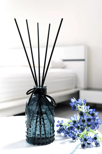 luxury aromatic scent of reed diffuser glass bottle is used as room freshener on the marble table in the bedroom to creat relax ambient with background of light from window and white bed in morning