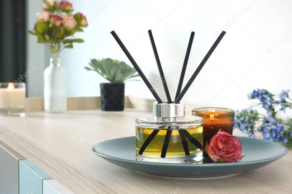 luxury aromatic scent reed diffuser glass bottle is used as room freshener on wooden table in the bedroom to create romantic and relax ambient with background of the flowers on the valentine day