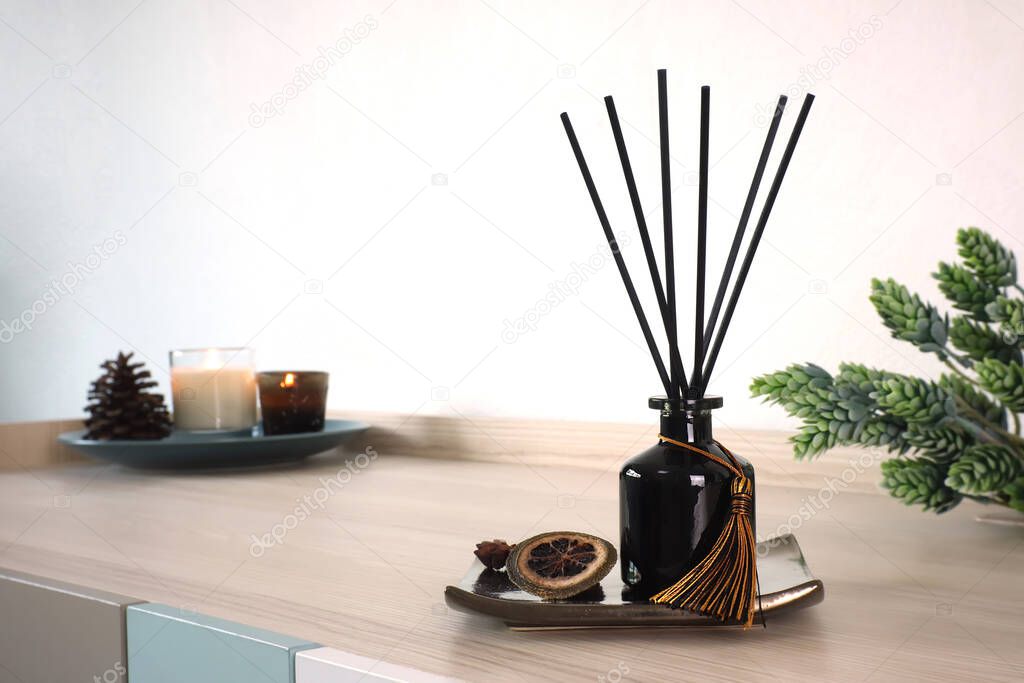 luxury aroma scent reed diffuser glass bottle is on the wooden table and amber glass of scented candle to creat romantic and relax ambient in the bedroom in the morning on happy valentine day