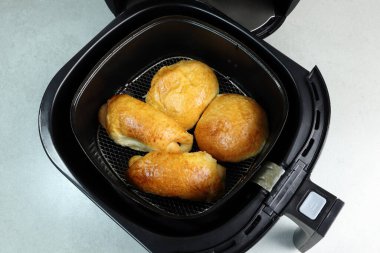 Ev yapımı ekmekler, mutlu bir aileyle Noel partisinde mutfaktaki gri masada kahvaltı için siyah hava kızartma makinesinde ya da yağsız fritözde pişirilir.