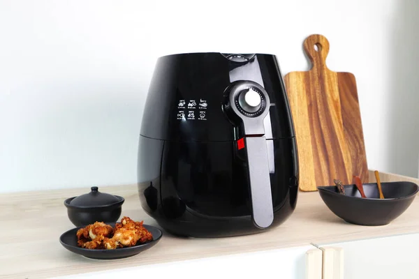 a black deep fryer or oil free fryer , air fryer appliance is on white  marble table