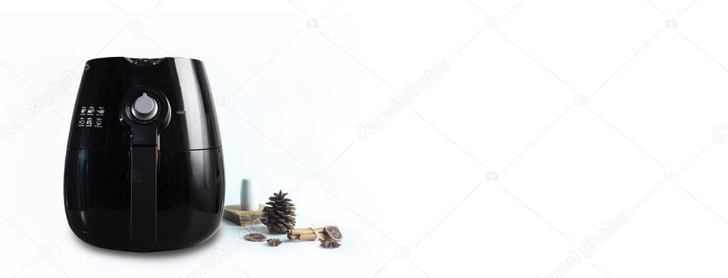 a black deep fryer or oil free fryer appliance is on white table with some spices in the kitchen ( air fryer ) with background of white cement wall